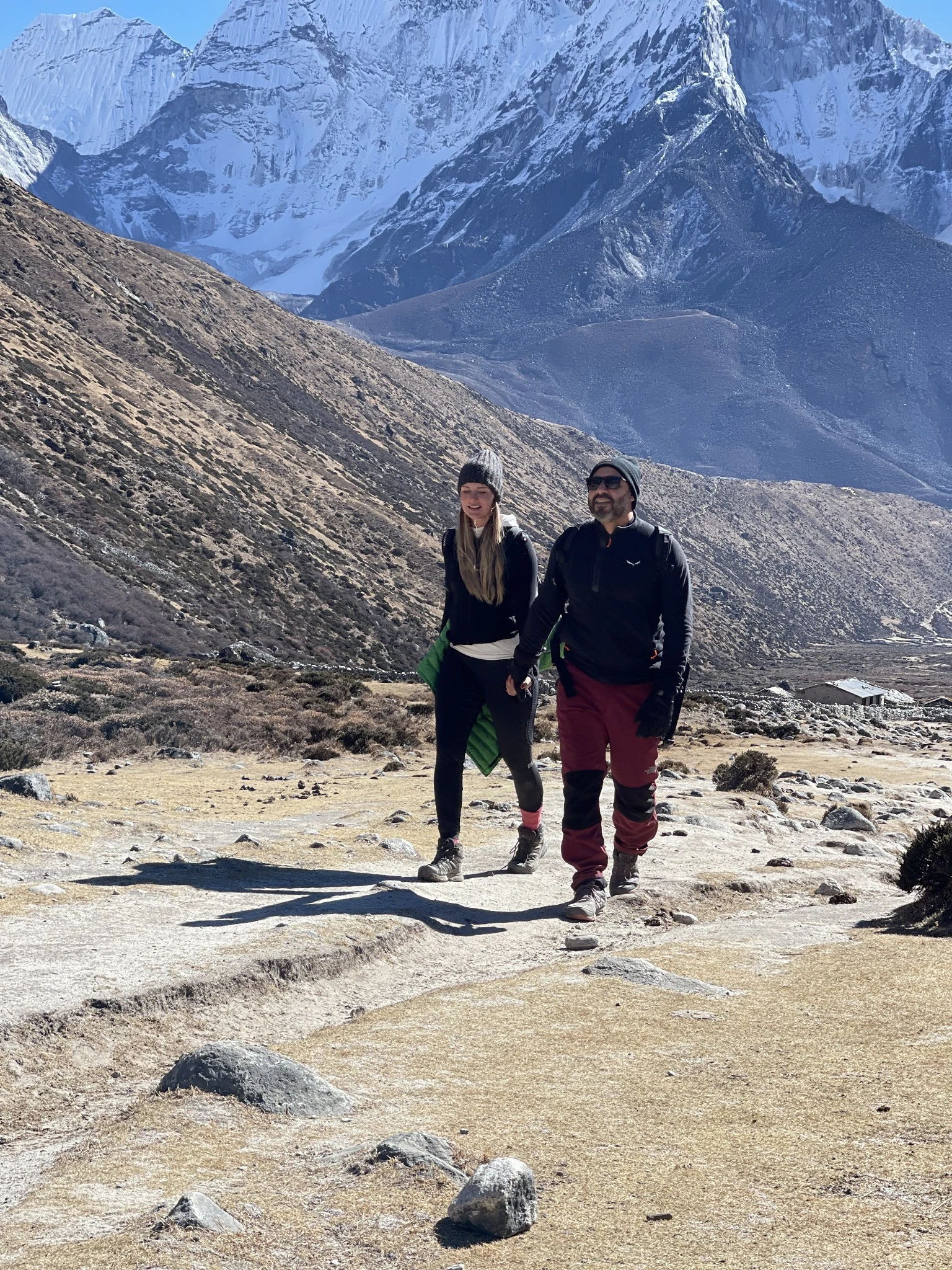 Marissa and a fellow adventurer walking beneath snow-covered Himalayan peaks in Nepal