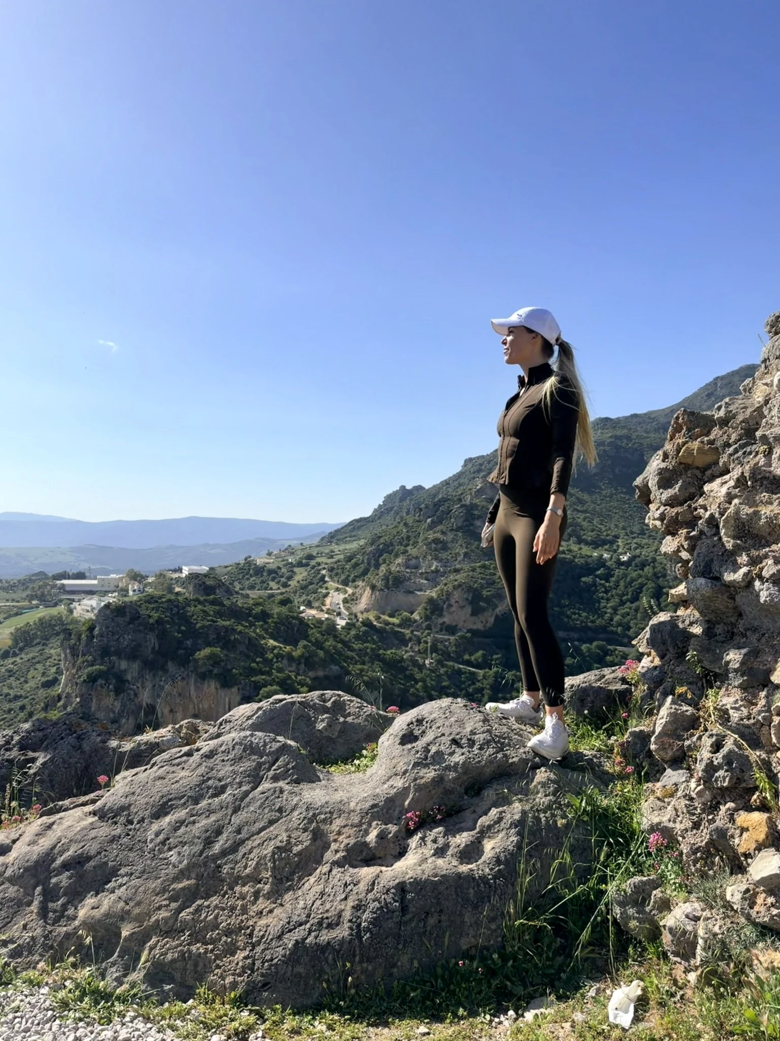 Marissa standing on a rocky viewpoint above green hills